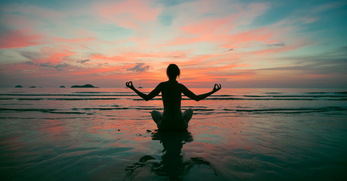 silhoutte of a woman meditating on the beach