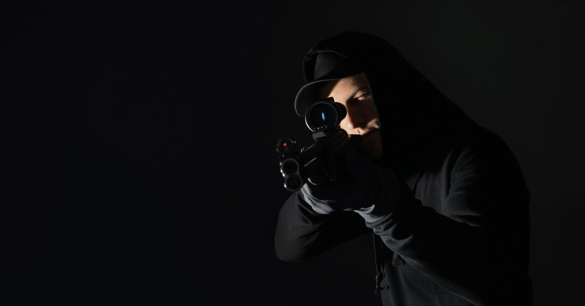 Professional killer with sniper rifle on black background