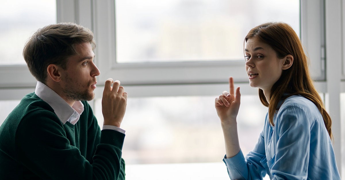 man and woman talking beside a window