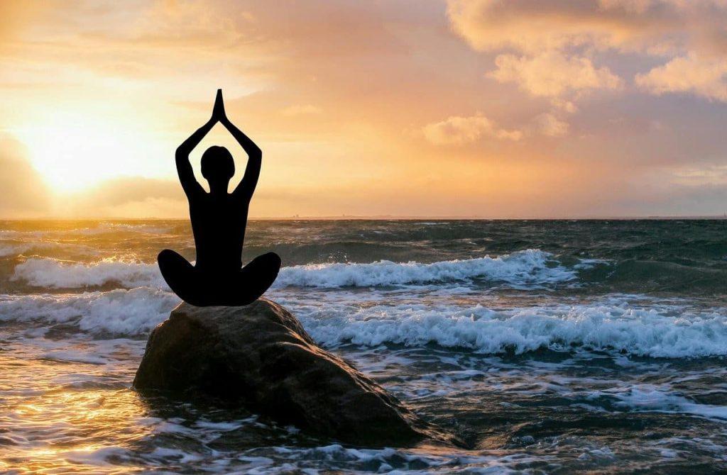 silhouette of a woman doing yoga on beach