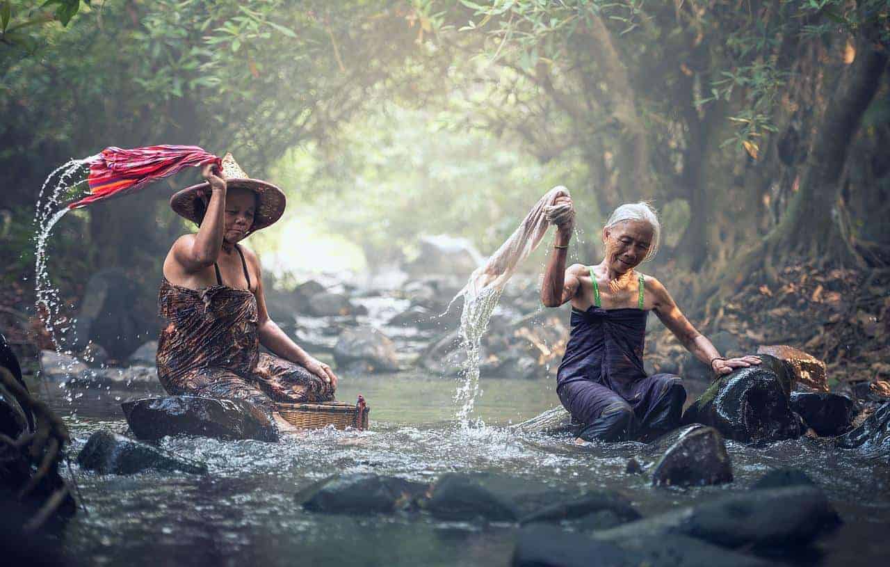 two old woman washing clothes in river