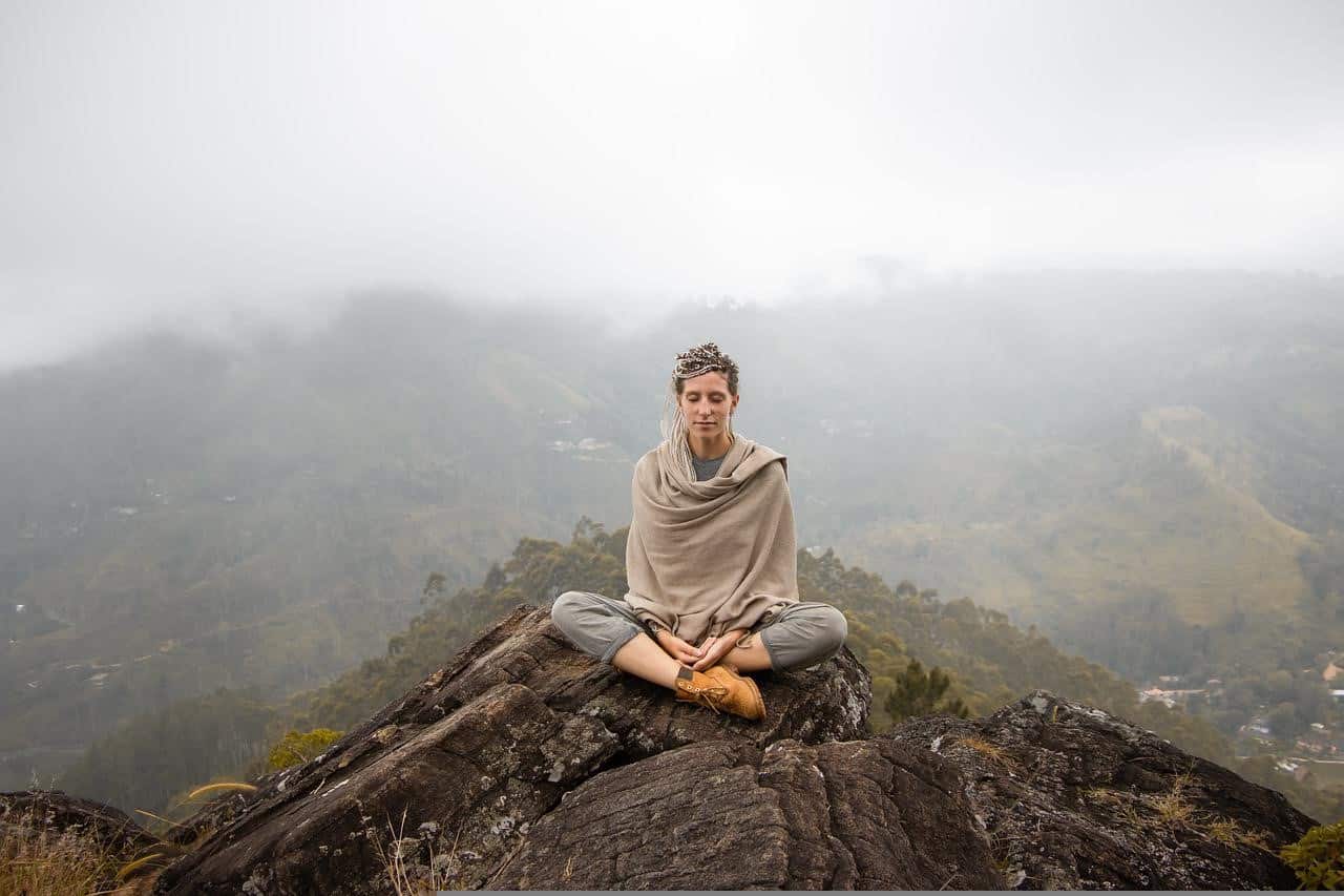 woman meditating on a rocky mountain