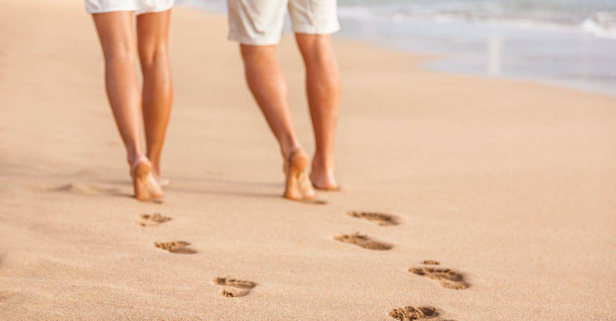 couple walking barefoot on sand
