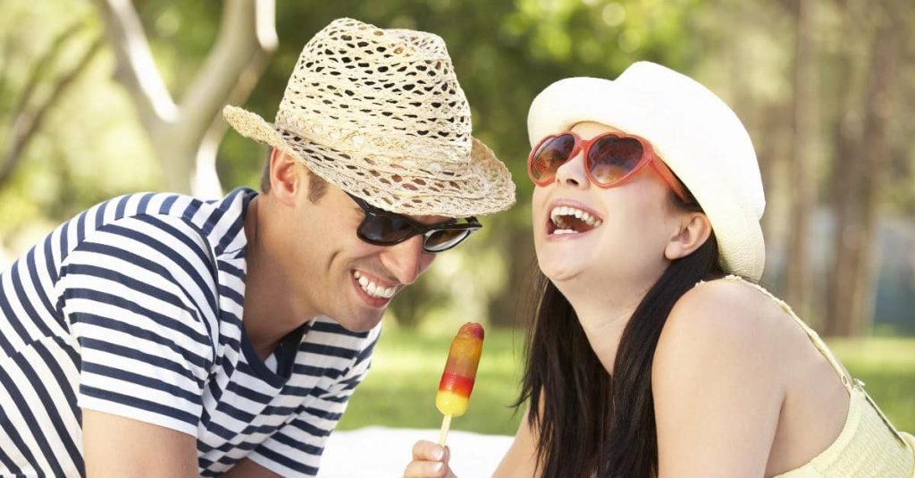 couple wearing hat and sunglasses laughing