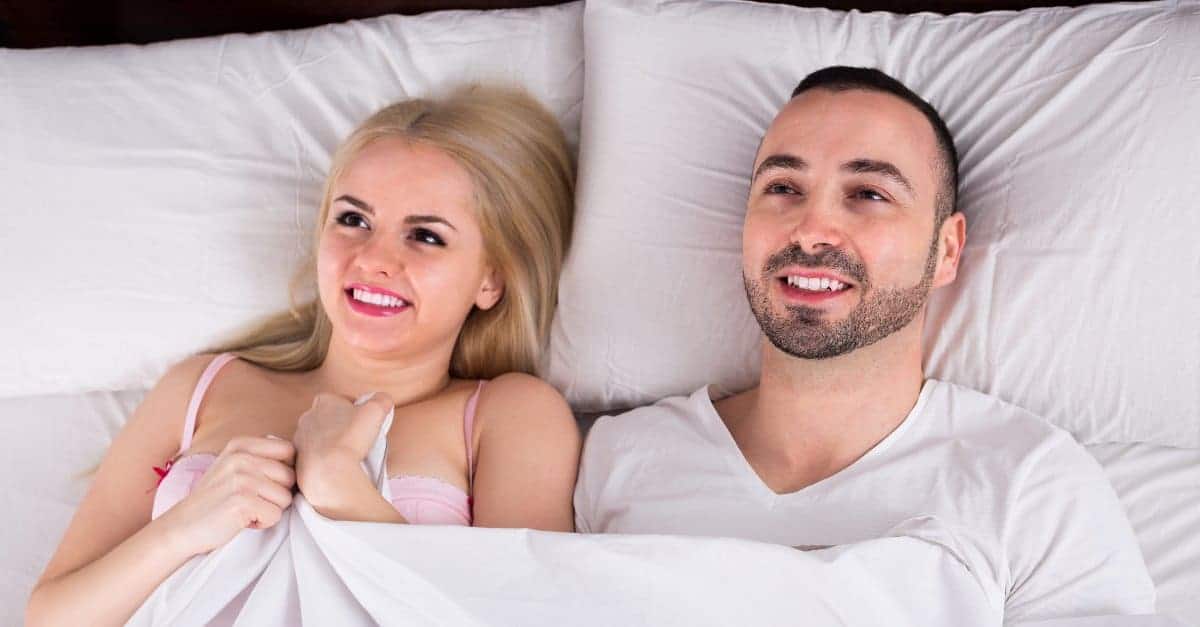 man and woman smiling in bed after sex