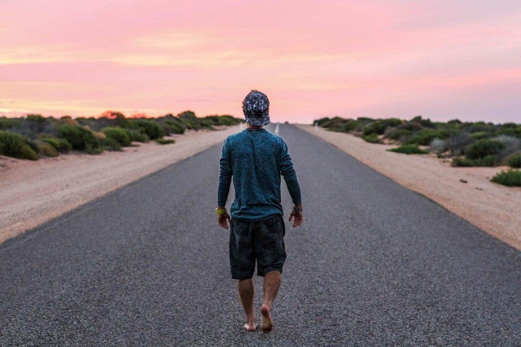 man walking barefoot on road