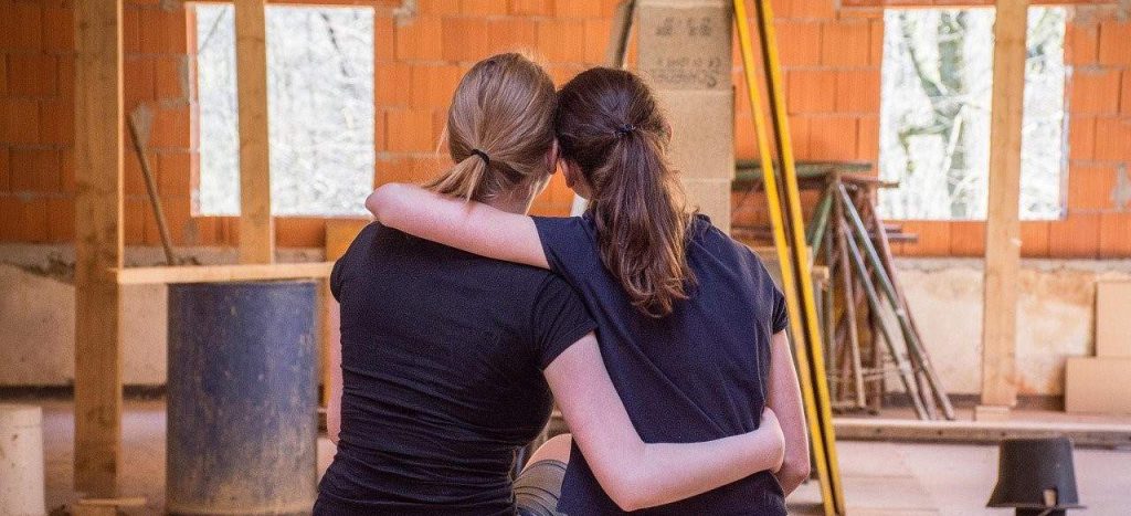 two woman sitting and hugging