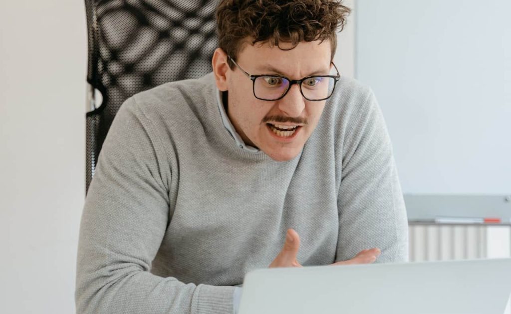 angry man wearing glasses and grey sweater