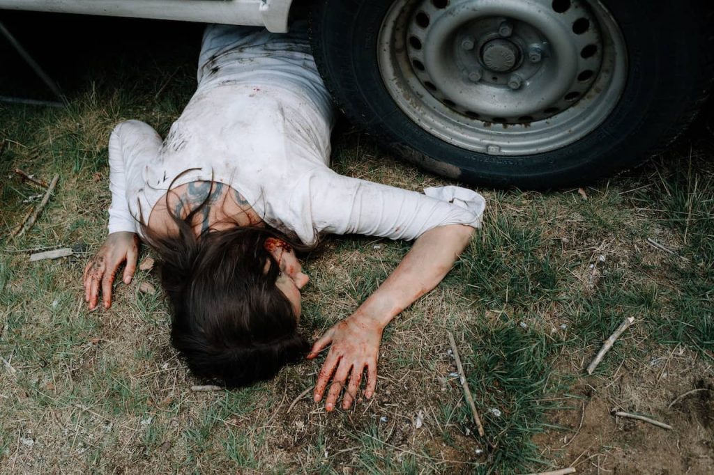 dead woman lying underneath a car