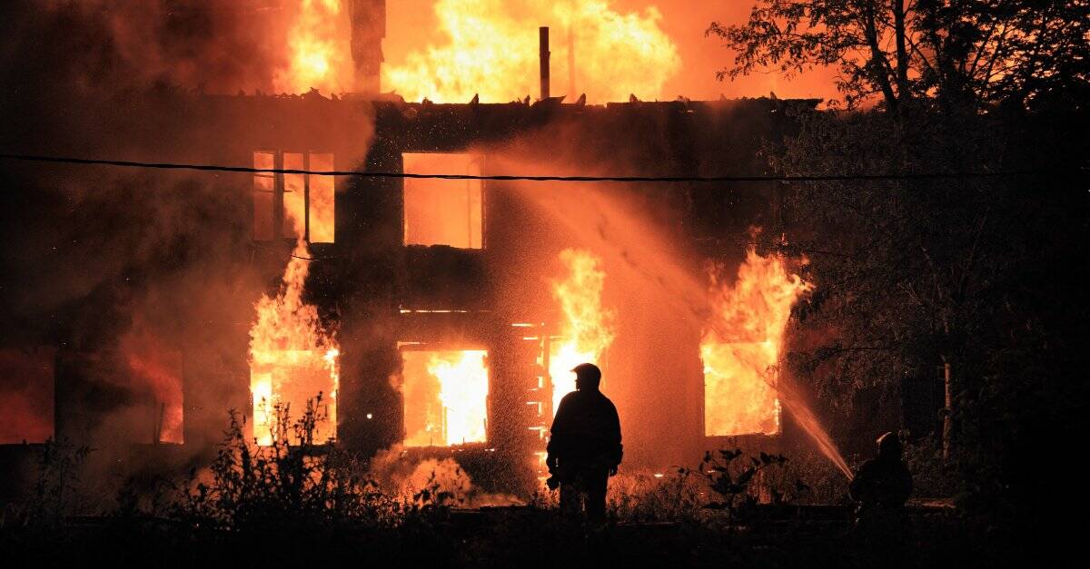 man standing in front of a burning house