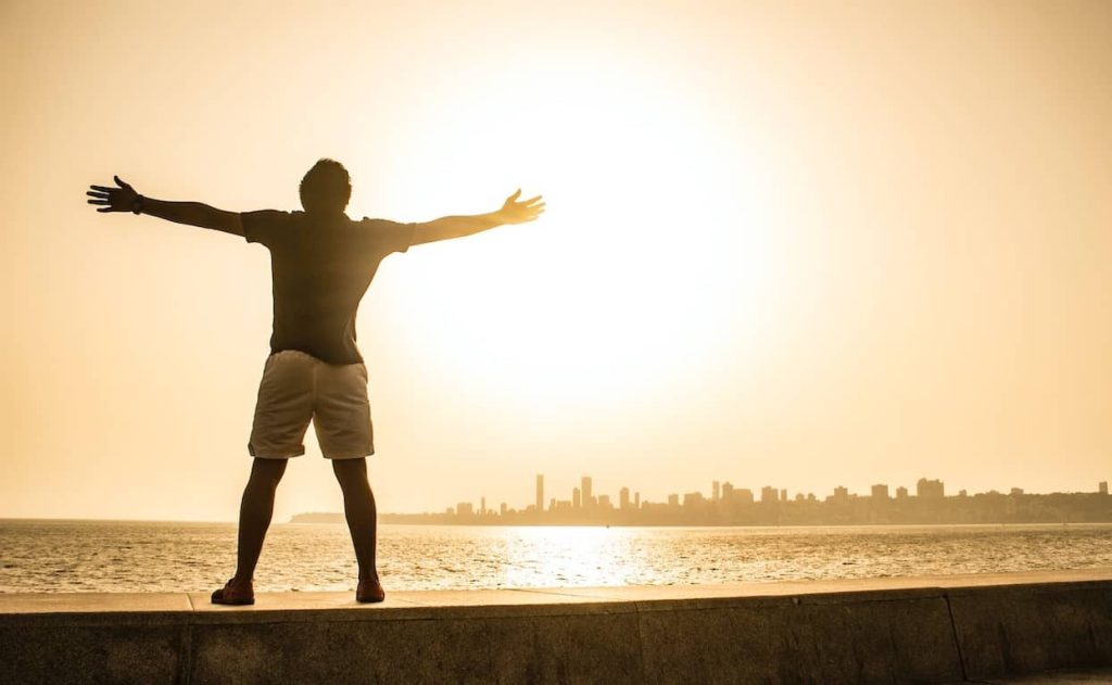 man standing on a ledge spreading his arms