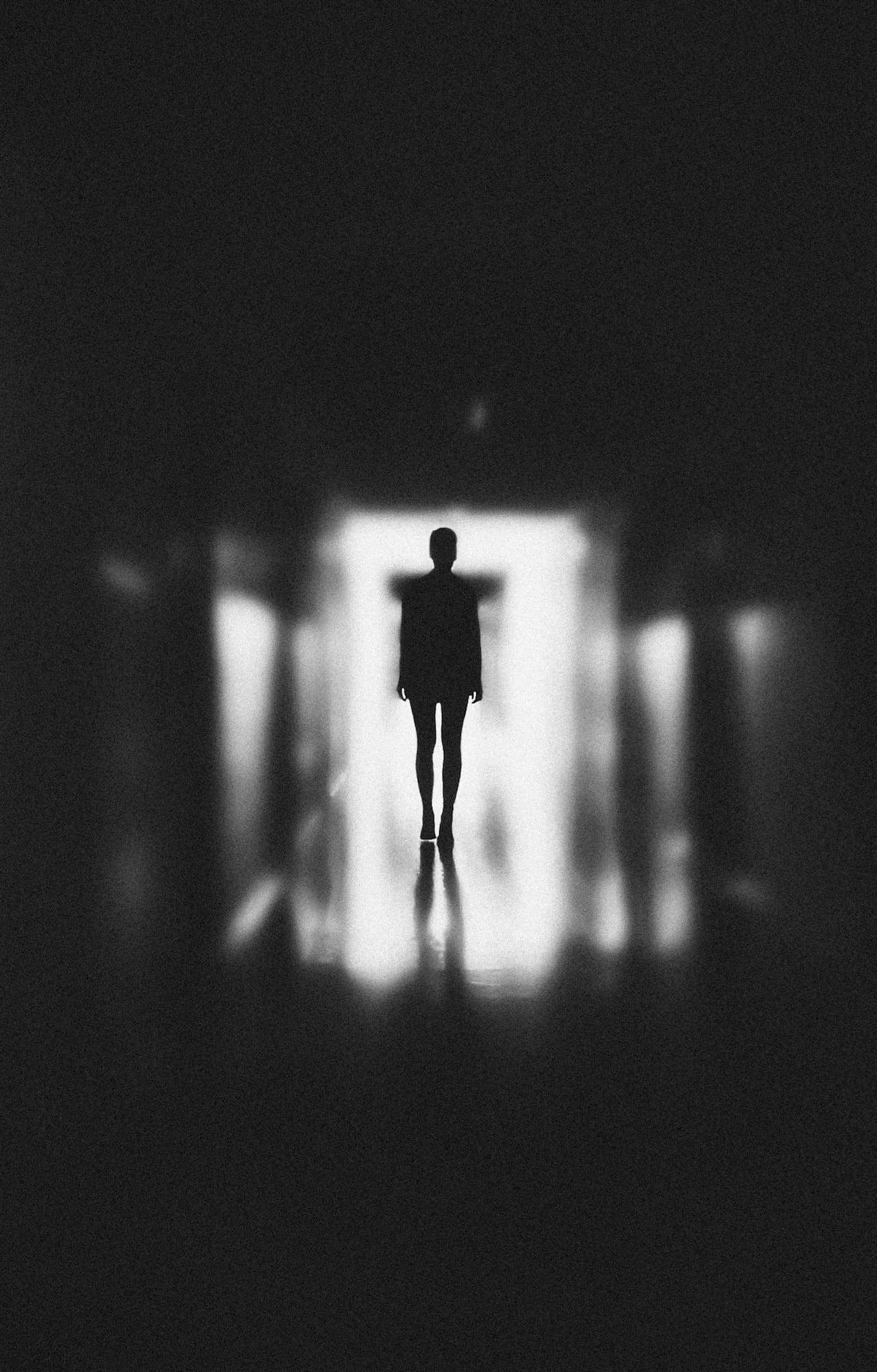 monochrome photo of a man standing on a hallway