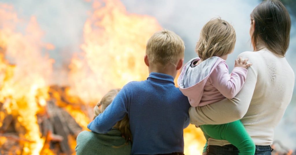 mother and children looking at their burning house