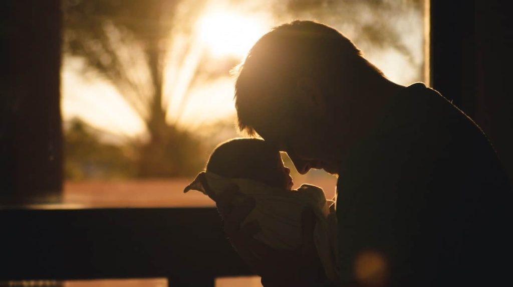 silhoutte of a man carrying a baby