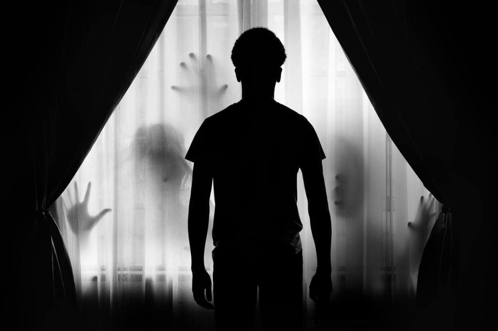silhoutte of a man with shadows trying to get to him
