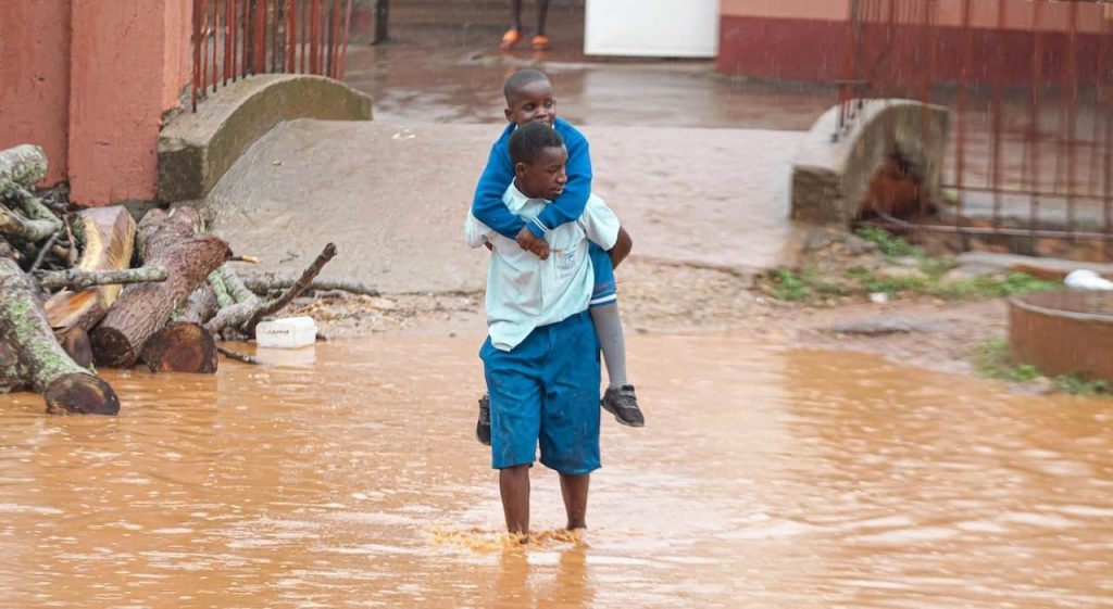 teenage boy carrying his brother during flood