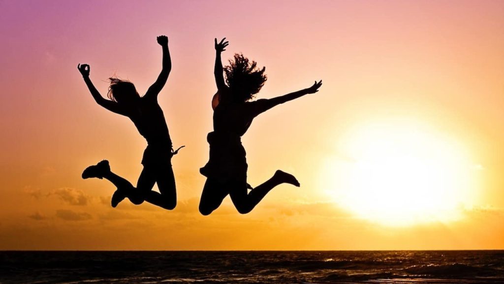 two woman jumping on a beach