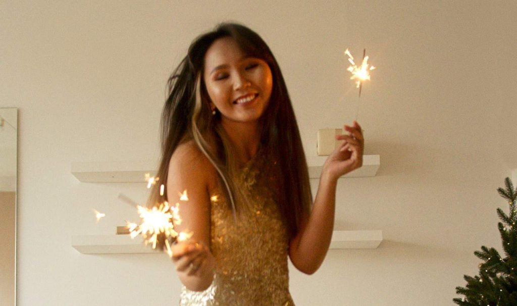 woman holding fireworks wearing gold dress
