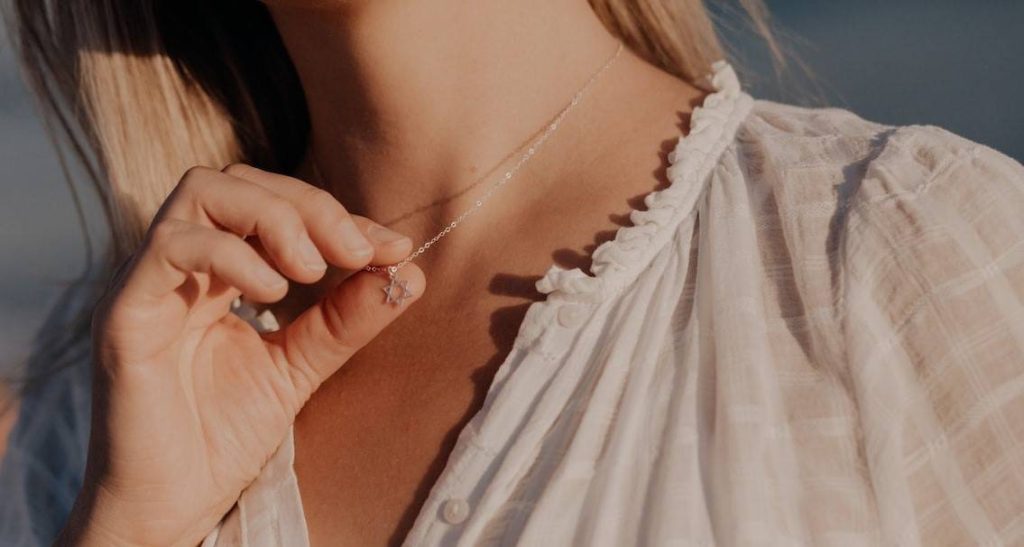 woman holding her silver necklace