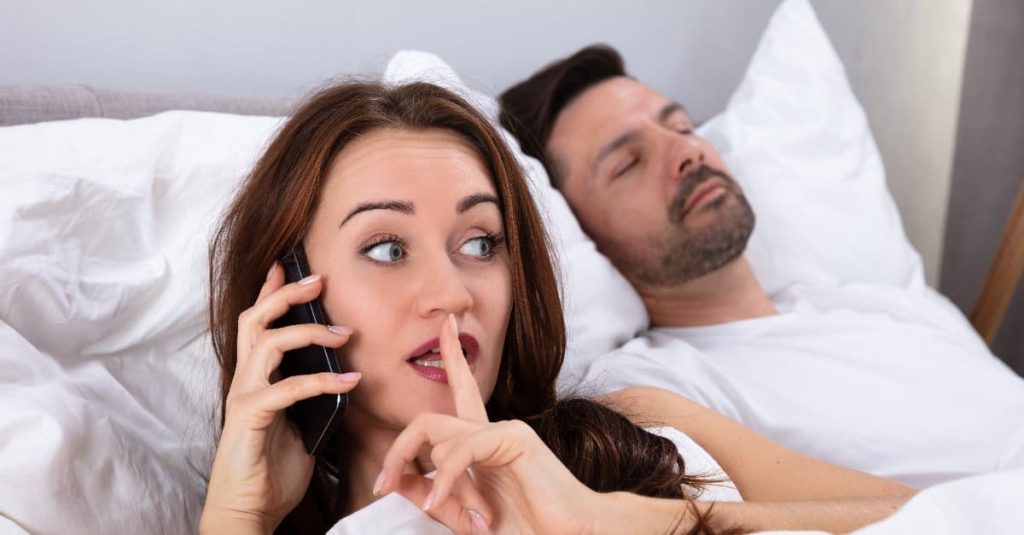 woman on the phone while husband is sleeping