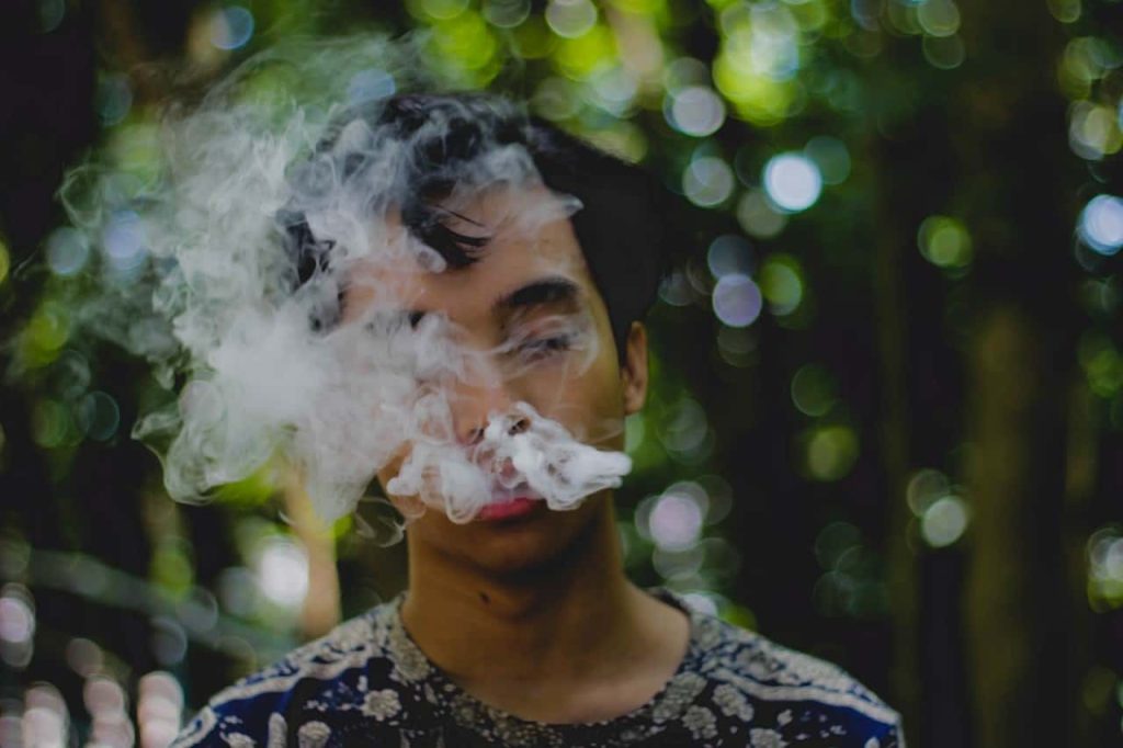 man breathing out smoke