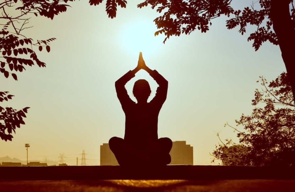 man meditating underneath a tree