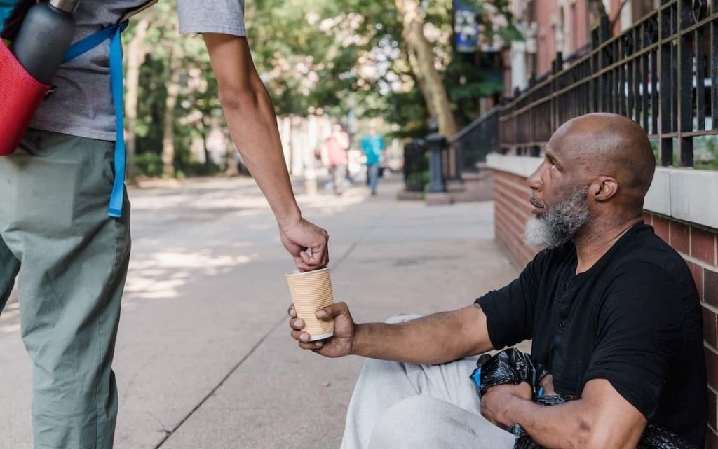 man putting coins in a homeless person's cup
