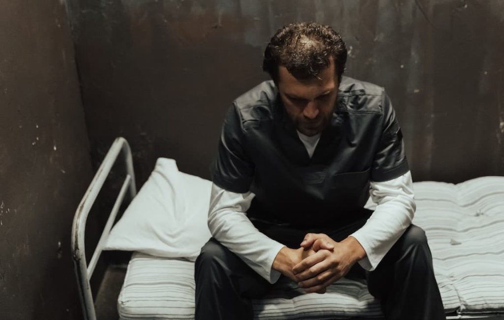 man sitting on a prison cell