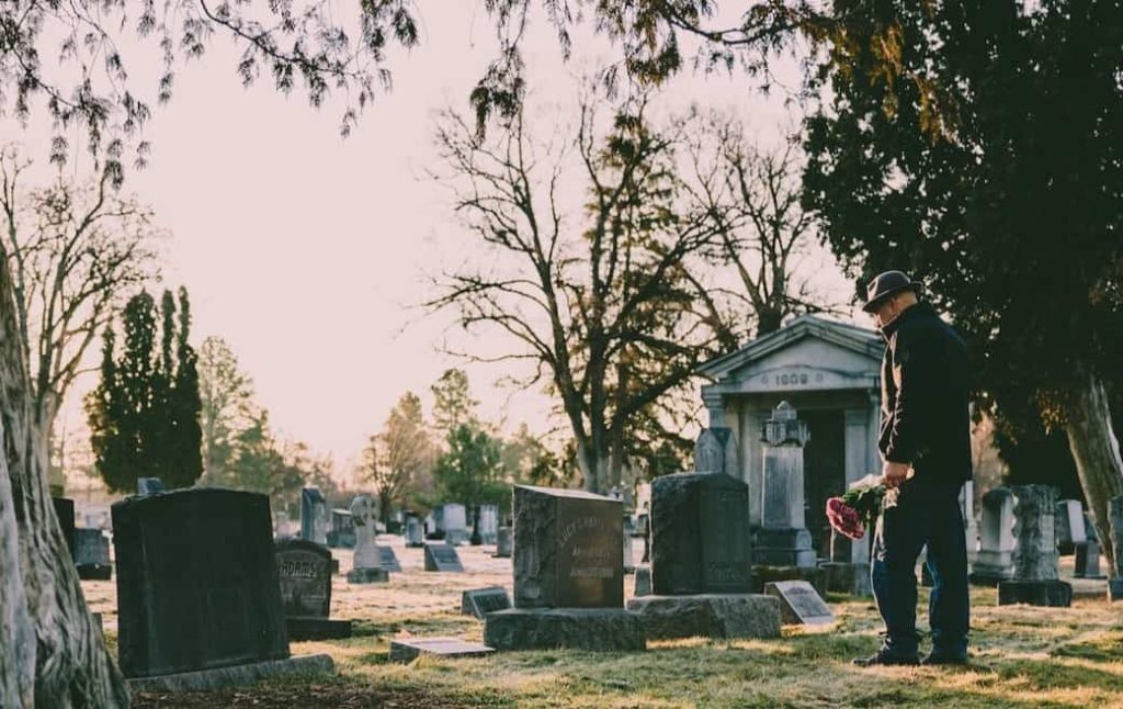 man standing in front of a grave