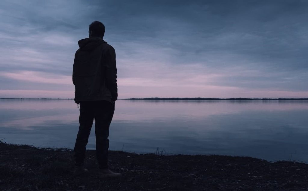 silhoutte of a man standing near a lake