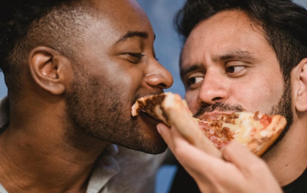two men eating pizza together