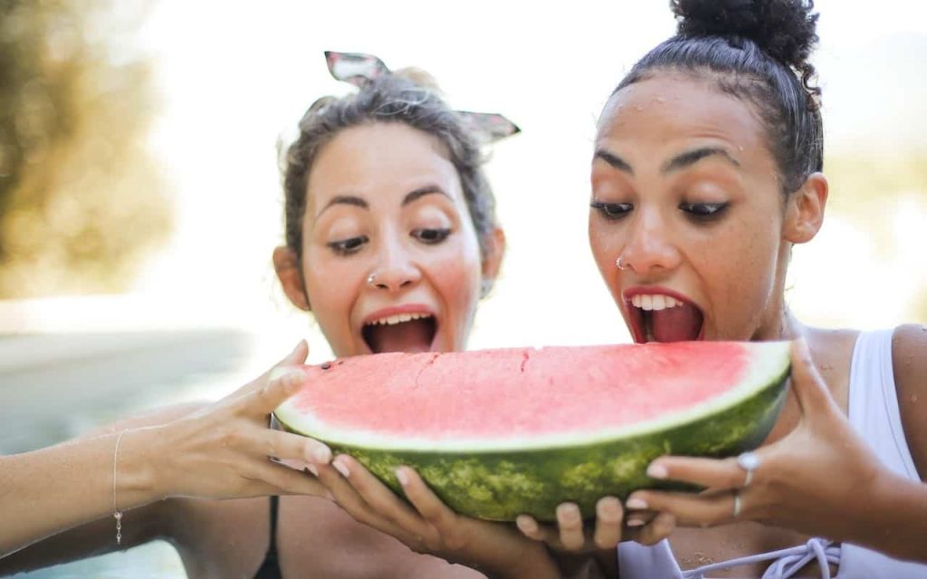 two woman eating watermelon