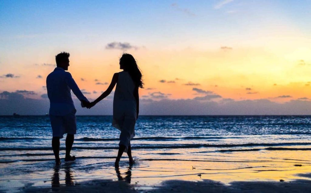 couple holding hands and walking at a beach