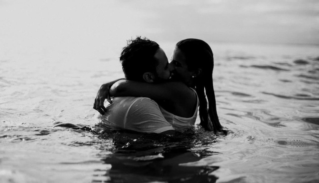 couple kissing on body of water