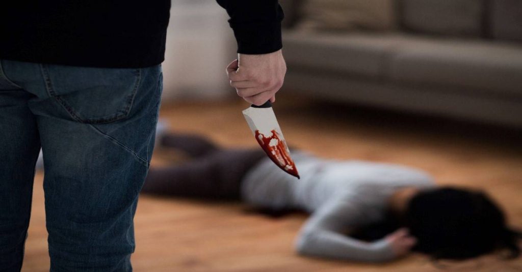 man holding a knife while woman lying on the floor