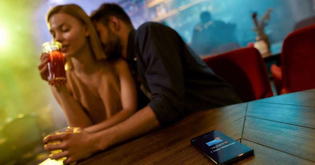 man kissing a woman's neck at a bar