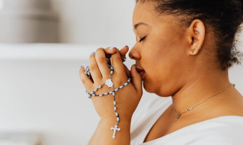 woman praying while holding a rosary