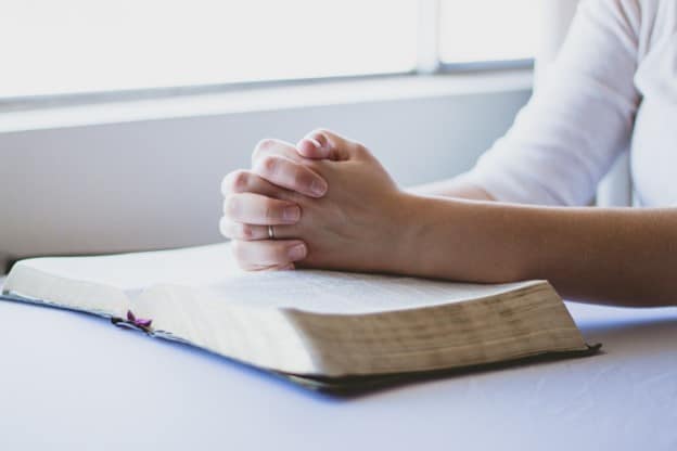 person's hand on top of bible